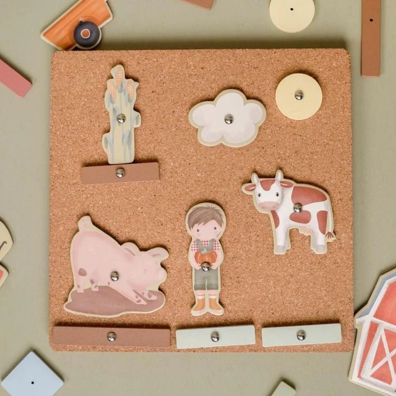 Cork board with farm-themed wooden cutouts including a cow, pig, and farmer on a beige background.
