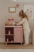 Child playing with a baby模拟器 in a pink play kitchen