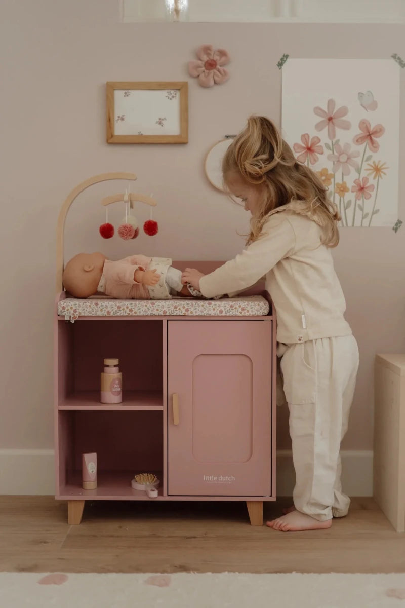Child playing with a baby模拟器 in a pink play kitchen