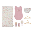 Collection of baby items including a floral crib sheet, pink dress, hat, hangers, and baby care products on a white background.