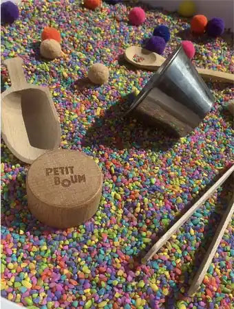 Sensory play with coloured rice and wooden scoops